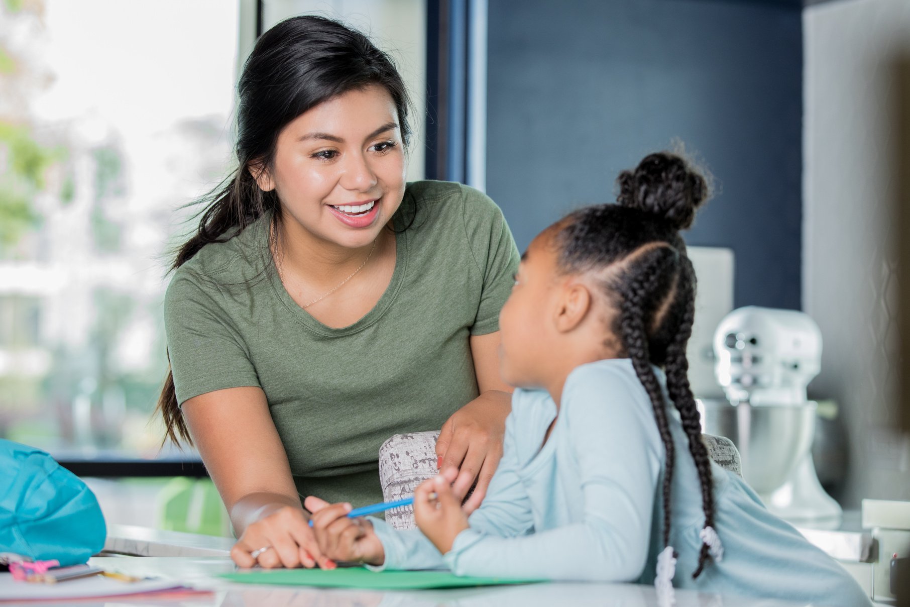 Happy young Hispanic woman is babysitting, tutoring elementary age girl.